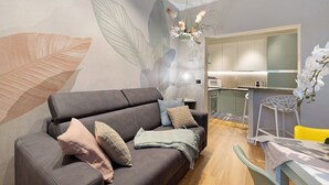 A modern living room with a sofa, a dining table, and a kitchen area. - Apartment 'Soleluna' with Wi-Fi and Air Conditioning (Vado Ligure)