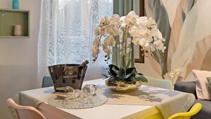 A dining table with a placemat, a decorative bowl, and a bottle of MONIVERT wine. - Apartment 'Soleluna' with Wi-Fi and Air Conditioning (Vado Ligure)
