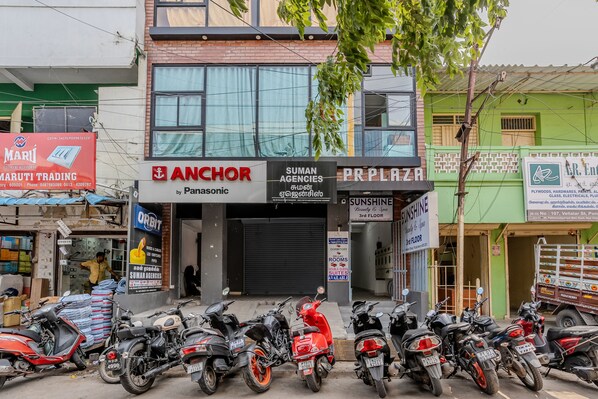 Il s’agit d’un immeuble abritant plusieurs commerces, notamment Anchor, Suman Agencies et Sunshine. Plusieurs motos sont garées devant.