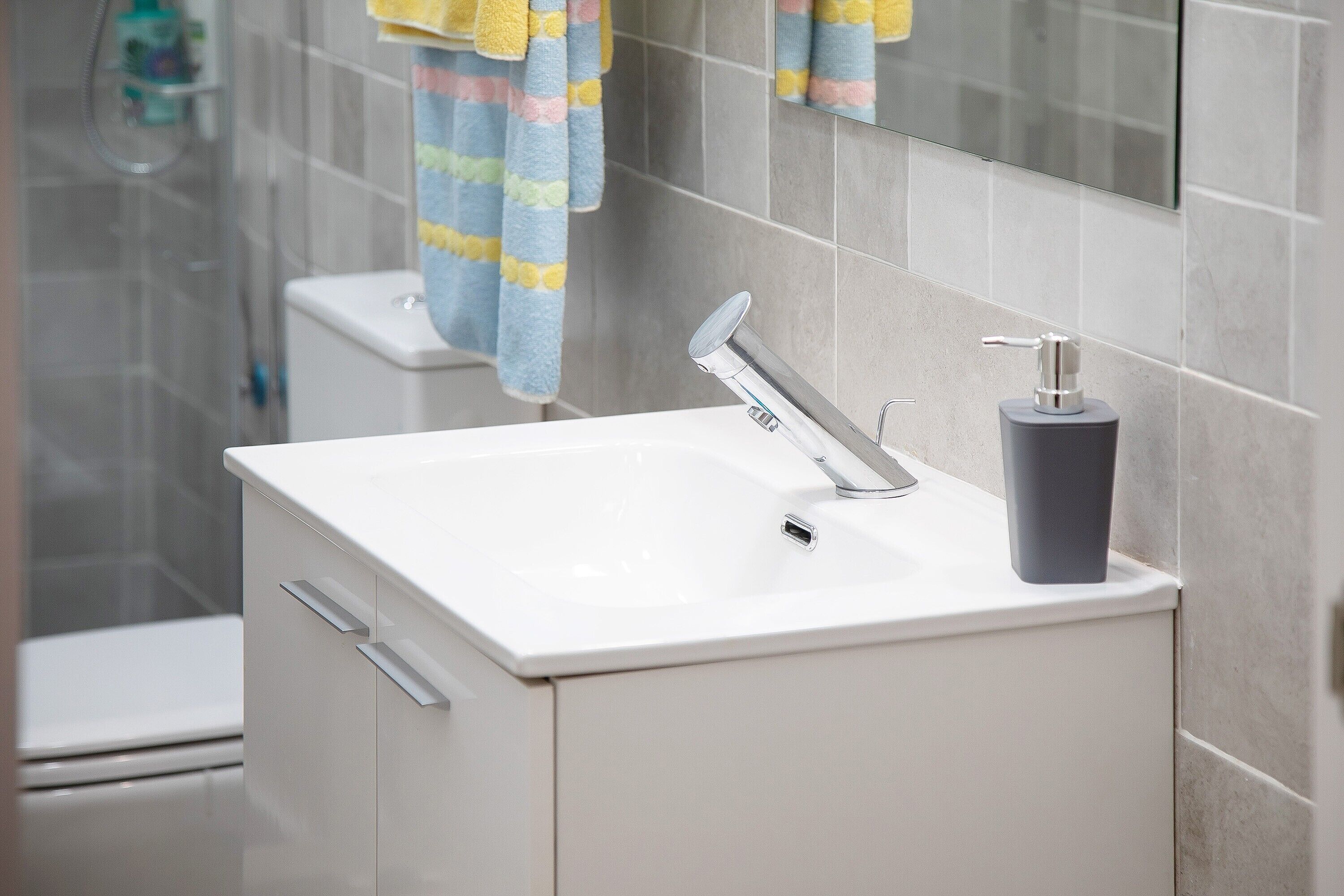 A bathroom with a white sink, a mirror, and a shower area.