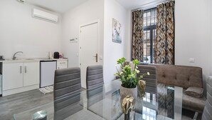 Cozinha moderna com armários brancos, lava-louças embutida e área de jantar com mesa e cadeiras de vidro.