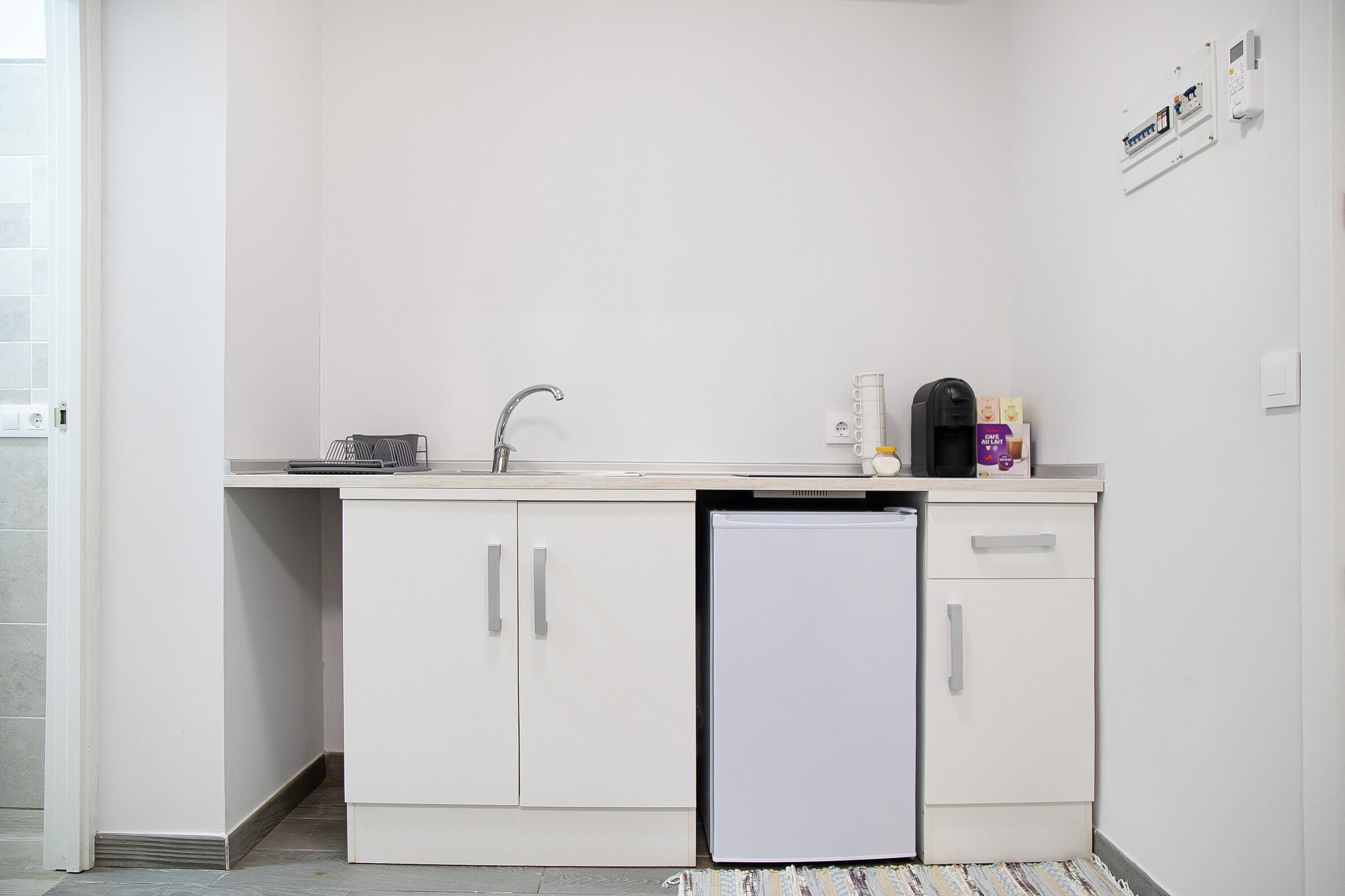 A small kitchenette with a refrigerator, sink, and cabinets.