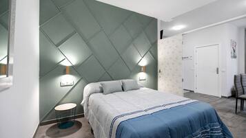Een slaapkamer met een bed, nachtlampjes, een rond tafeltje en een deur.