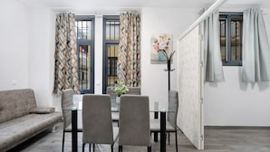 Uma sala de estar moderna com sofá, mesa de jantar, cadeiras e uma mesa de centro de vidro.