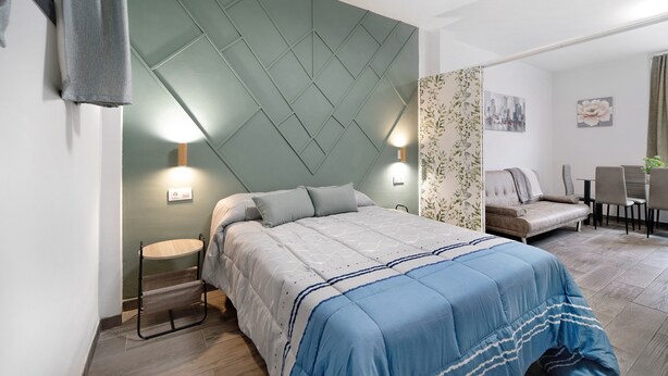 A modern bedroom with a bed, bedside lamps, a small table, and a sofa. - Apartment 'Centro Jerezano 2' with Wi-Fi and Air Conditioning (JEREZ DE LA FRONTERA)