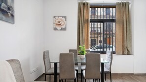 A dining area with a glass table, six chairs, a potted plant, and a window with curtains. - Apartment 'Centro Jerezano 2' with Wi-Fi and Air Conditioning (JEREZ DE LA FRONTERA)