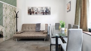 A modern living room with a sofa, dining table, chairs, a cityscape painting, and a plant. - Apartment 'Centro Jerezano 2' with Wi-Fi and Air Conditioning (JEREZ DE LA FRONTERA)