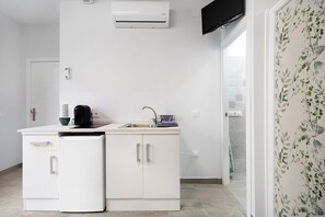 A compact kitchen with a built-in dishwasher, a coffee maker, and a small sink.