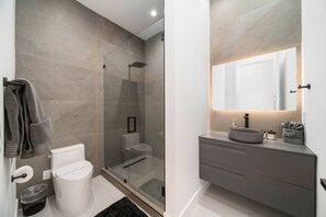 A modern bathroom with a glass-enclosed shower, a toilet, and a vanity with a mirror. - Elements Luxury Home with Pool and Hot Tub Near the Beach (Fort Lauderdale)