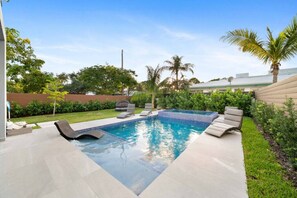 A rectangular swimming pool with a tiled edge, surrounded by a concrete deck. There are lounge chairs and a small hot tub. - Elements Luxury Home with Pool and Hot Tub Near the Beach (Fort Lauderdale)