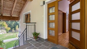 A wooden staircase leading to a door, a small potted plant, and a view of a garden. - Apartment 'Funtnatsch Langkofel' with Mountain View, Shared Garden and Wi-Fi (Laion)