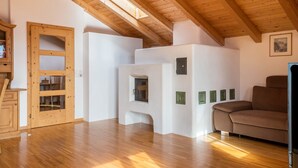 A room with wooden beams, a wooden cabinet, a brown sofa, and a white wall with a small window. - Apartment 'Funtnatsch Langkofel' with Mountain View, Shared Garden and Wi-Fi (Laion)