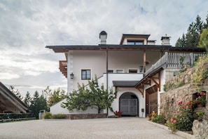 Un edificio di due piani con facciata in pietra, un balcone in legno e un ampio ingresso ad arco.