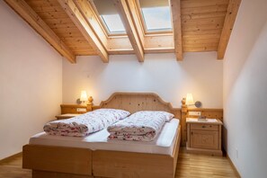 A bedroom with a wooden bed, two bedside tables with lamps, a skylight, and a wooden wardrobe. - Apartment 'Funtnatsch Schlern' with Mountain View, Shared Terrace and Wi-Fi (Laion)