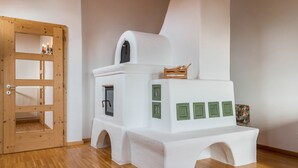 Una habitación con puerta de madera, pared blanca y una estructura blanca que recuerda a una pequeña construcción o casita, con detalles en verde.