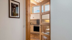 Puerta de madera que da a una cocina con estufa, una ventana y un cuadro en la pared.