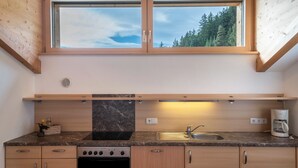 Una cocina con ventana, estufa, lavaplatos y cafetera.