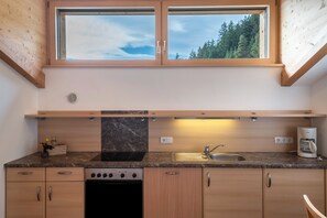 A kitchen with a window, a stove, a sink, and a coffee maker.