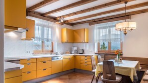 A kitchen with yellow cabinets, a dining table with chairs, and a chandelier.