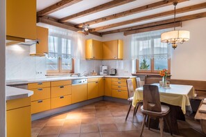 A kitchen with yellow cabinets, a dining table with chairs, and a chandelier.