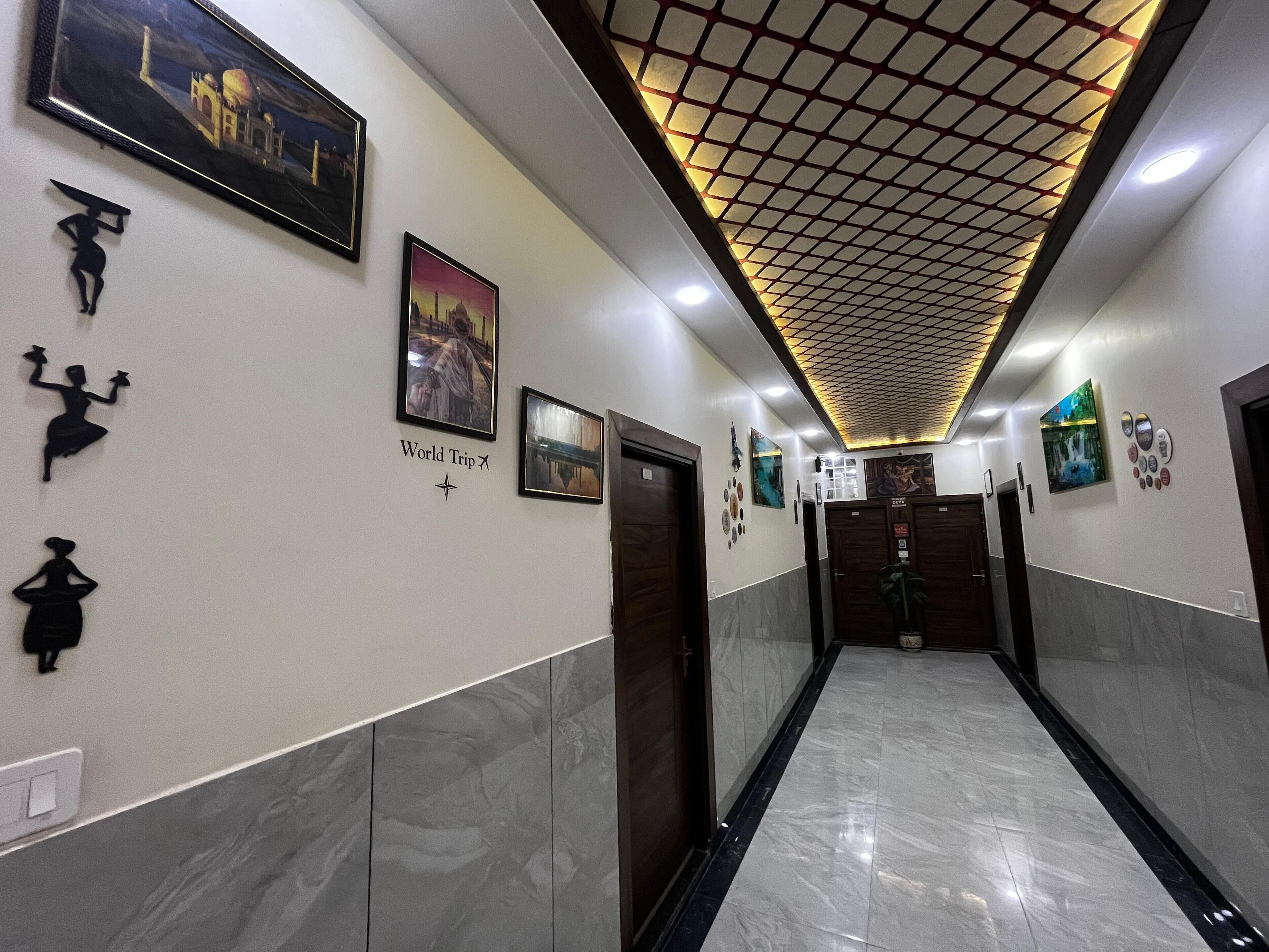A hallway with framed pictures, a 'World Trip' sign, and a CCTV sign.