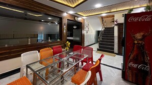 Un espace repas moderne avec une table en verre et des chaises rouges, un escalier et un réfrigérateur Coca-Cola.