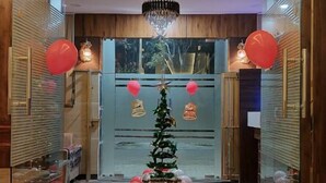 Un hall d’entrée décoré d’un sapin de Noël, de ballons rouges et d’une horloge murale.
