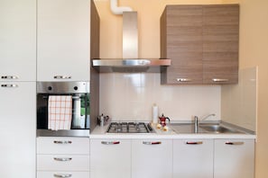 A modern kitchen with a gas stove, stainless steel range hood, and a built-in oven.