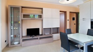 Een moderne keuken met een eettafel, stoelen, een televisie en inbouwmeubels.
