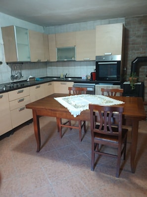 A kitchen with a dining table, chairs, cabinets, a stove, and a television. - Apartment "Casa del Moro" with Private Terrace & Wi-Fi (Cantagrillo)