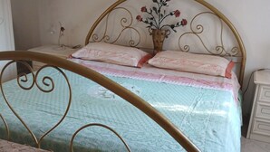A bedroom with a metal-framed bed, a bedside table, a lamp, and a framed picture on the wall.