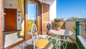 Ein Balkon mit Tisch und Stühlen, eine Holztür und Blick auf die Stadt.