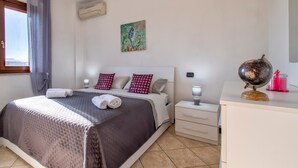 Ein ordentlich eingerichtetes Schlafzimmer mit Bett, Nachttischen, einem Globus und einem Gemälde an der Wand.