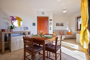 Un coin repas avec une table et des chaises en bois, une orchidée en pot et un miroir au mur.
