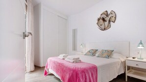 A bedroom with a bed, bedside tables, a mirror, and a decorative wall piece.