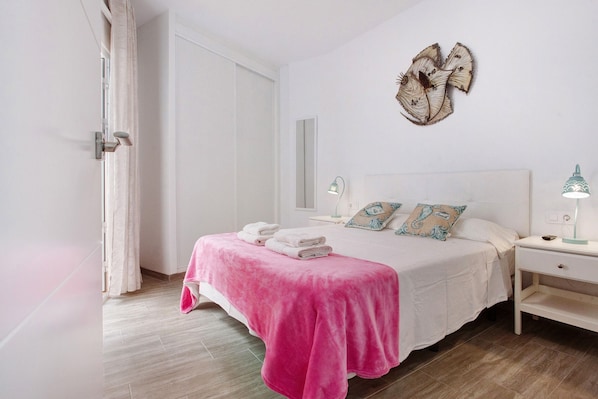 A bedroom with a bed, bedside tables, a mirror, and a decorative wall piece.