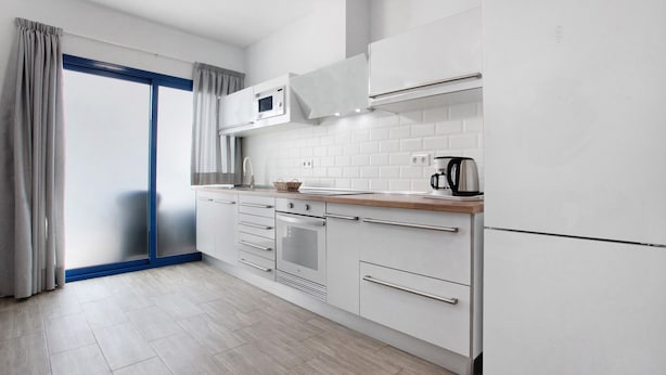 A modern kitchen with white cabinetry, a microwave, oven, and a coffee maker.