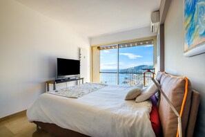 Una camera d'albergo con un letto, una televisione, una finestra vista e un quadro appeso al muro.