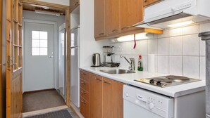 Eine kompakte Küche mit Holzausstattung, einem eingebauten Geschirrspüler und einem Herd.