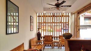 A traditional room with wooden furniture, a ceiling fan, and a decorative screen.