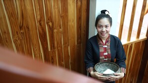 A person holding a patterned bowl in a room with wooden paneling.