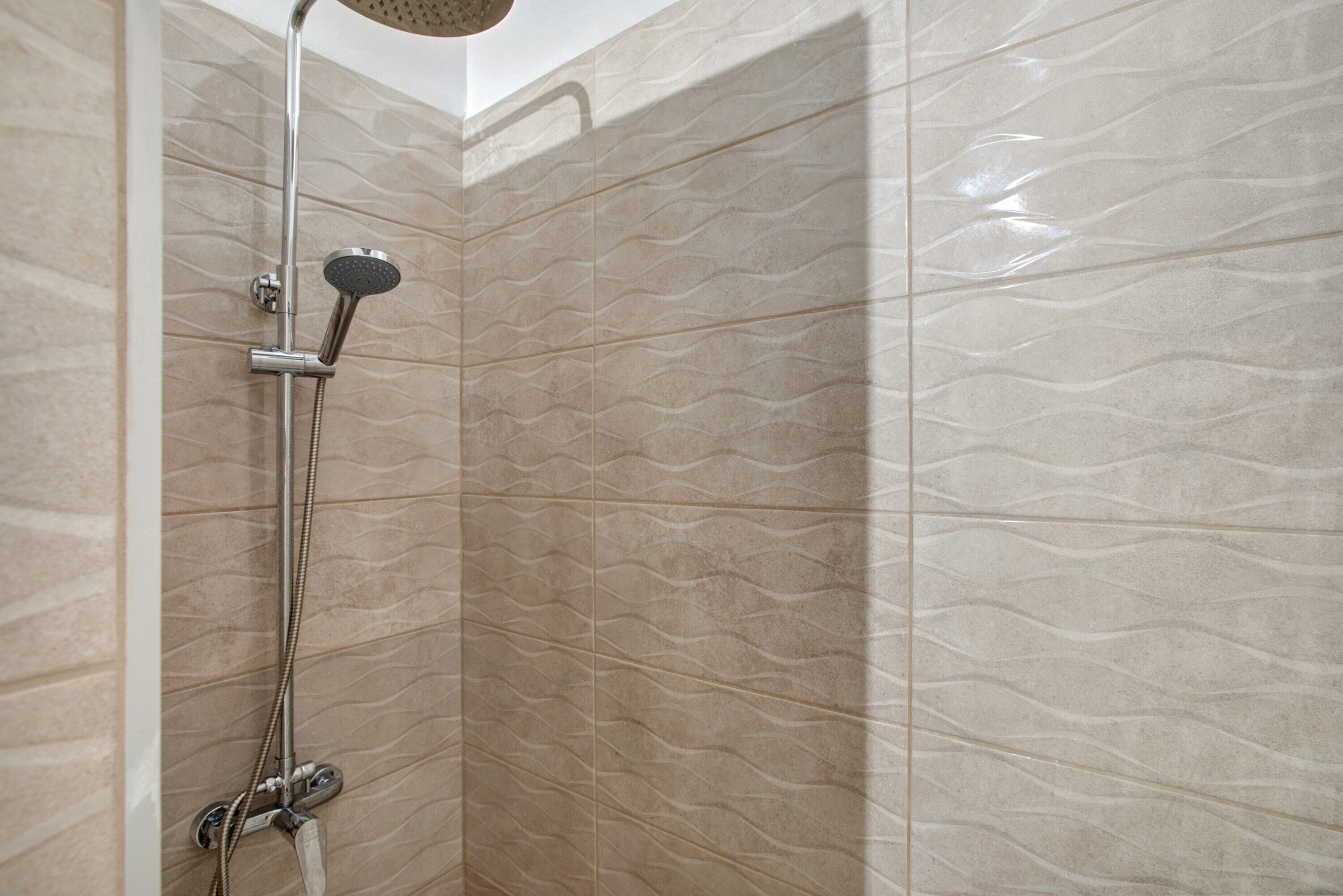 Een douche met een handdouche en een kraan aan de muur.