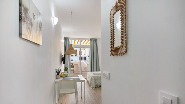A modern interior with a dining area, a bed, a wall-mounted mirror, and a painting. - Vacation Home "Estudio Sagrario" with Shared Pool (Arona)