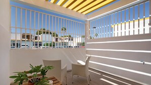 A balcony with a view of buildings, a wooden table with a potted plant, and two wicker chairs. - Vacation Home "Estudio Sagrario" with Shared Pool (Arona)