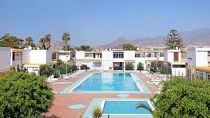 A pool area with a view of mountains, surrounded by buildings with a modern architectural style. - Vacation Home "Estudio Sagrario" with Shared Pool (Arona)