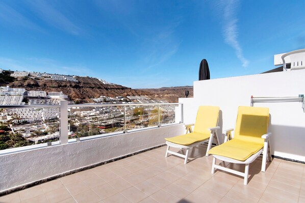 A balcony with two yellow chairs and a view of a town.