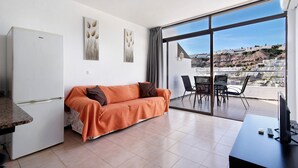 Quarto moderno com sofá, mesa de jantar e uma ampla janela com vista para a cidade.