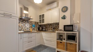 A modern kitchen with white cabinets, a patterned backsplash, a microwave, a coffee maker, and a small shelf with baskets. - Apartment 'Casa Cordemar Alghero' with Private Terrace, Wi-Fi and Air Conditioning (Alghero)