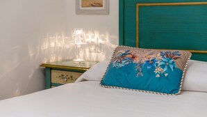 A bed with a floral pillow, a bedside lamp, and a framed picture on the wall. - Apartment 'Casa Cordemar Alghero' with Private Terrace, Wi-Fi and Air Conditioning (Alghero)