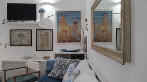 Een kamer met een bed, een bureau, een televisie, lijstwerk en een grote spiegel.
